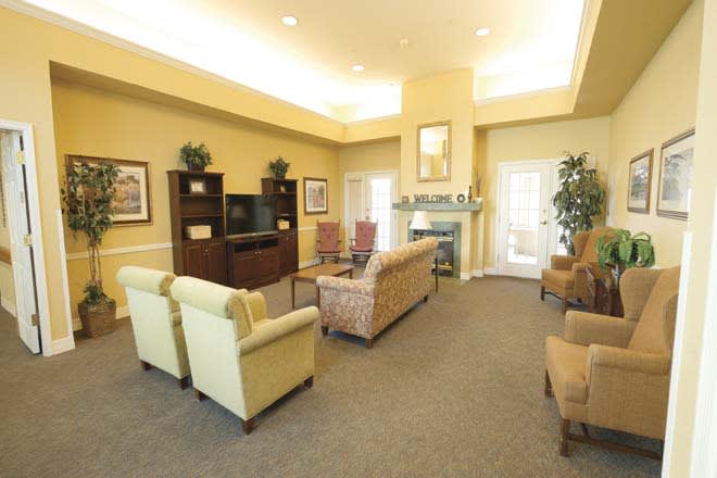 A cozy living room with sofas, armchairs, a television, and warm lighting.