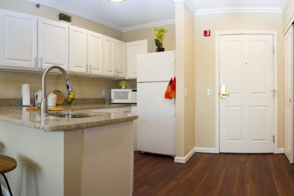 A modern kitchen interior featuring a refrigerator, microwave, and stone countertop.