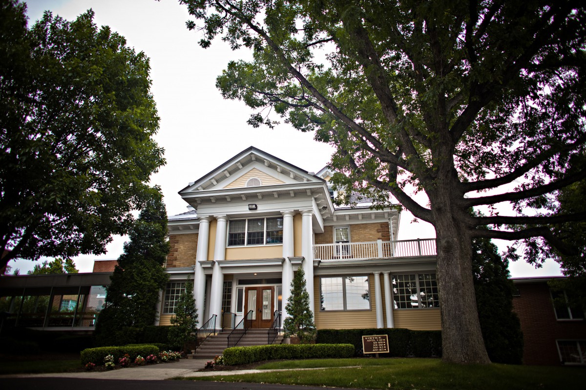 A historic building with columns and surrounding trees.
