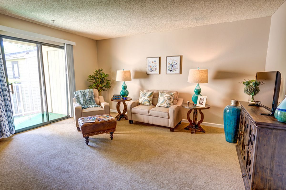 A cozy and well-decorated living room featuring a sofa, lamps, artwork, and decorative accents.