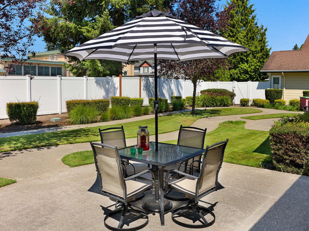 A patio set with a striped umbrella and four chairs on a sunny day.