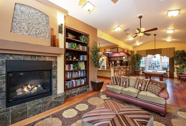 A cozy living room with a fireplace, bookshelves, and a comfortable sofa in an open-concept home.