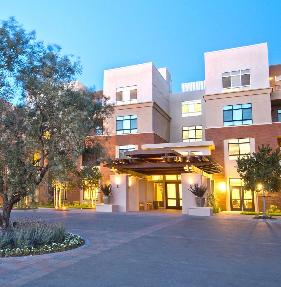 A modern hotel building with landscaped surroundings and a well-lit entrance.