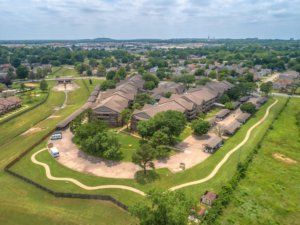 Aerial view of a residential area with apartments surrounded by greenery and a winding path.