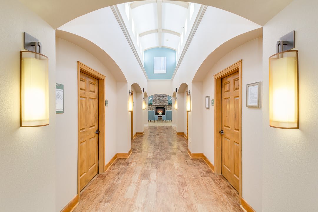 A brightly lit hallway with wooden doors and an arched ceiling.