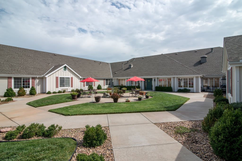 A building with a landscaped courtyard featuring red umbrellas and well-maintained lawns.