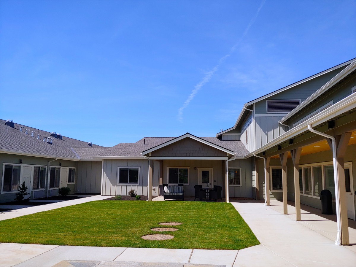 A view of a residential courtyard with a well-maintained lawn under a clear blue sky.