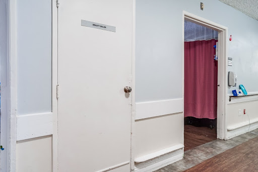 A restroom door next to a curtained area in a well-lit interior space.