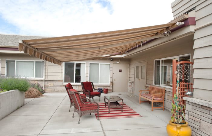 An outdoor patio with comfortable seating and a shade sail providing cover.