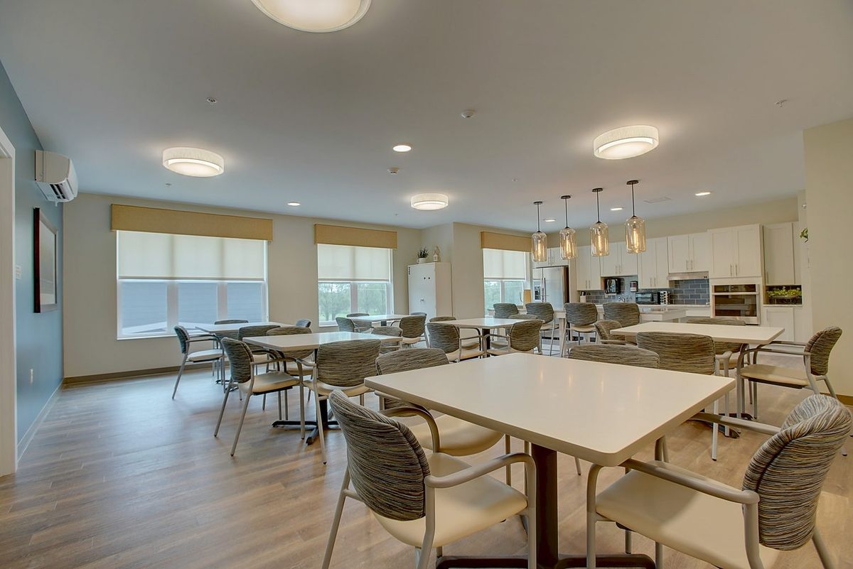 A modern dining area with wooden flooring and ample natural light.