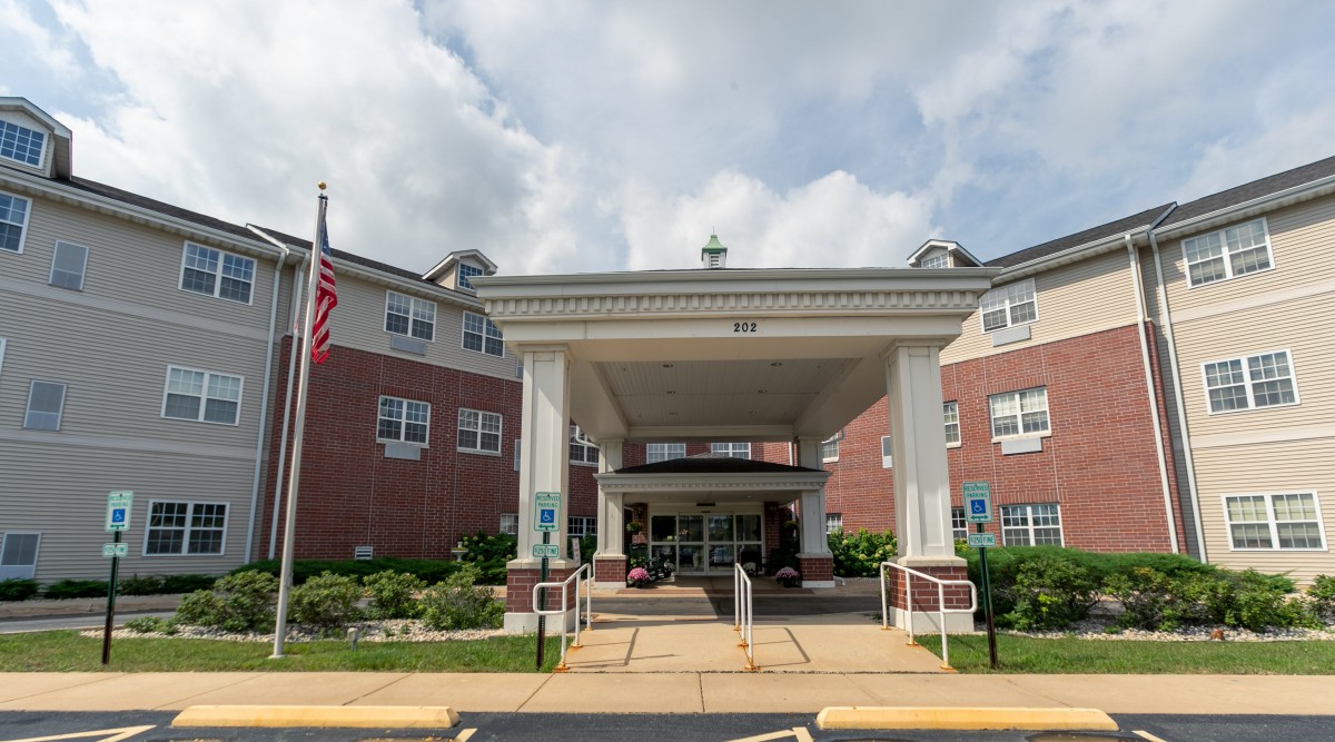 The entrance of a brick residential facility under an overcast sky.