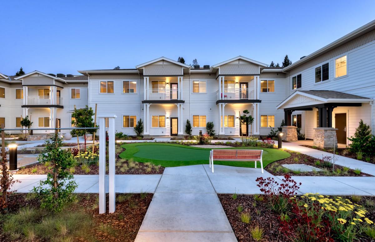 A modern apartment building with well-maintained landscaping and a central pathway.