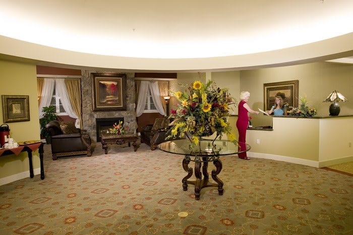 A cozy hotel lobby featuring a reception desk, elegant seating area, and a large floral centerpiece.