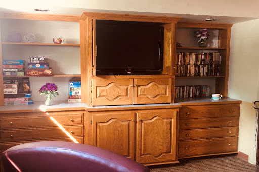A wooden entertainment center with a television and shelves, designed for a cozy living room setting.