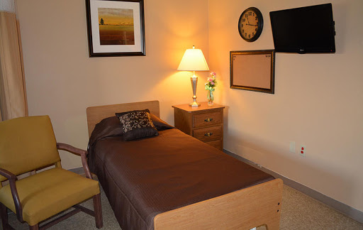 A cozy and simple bedroom layout featuring a single bed, lamp, and decorative elements.