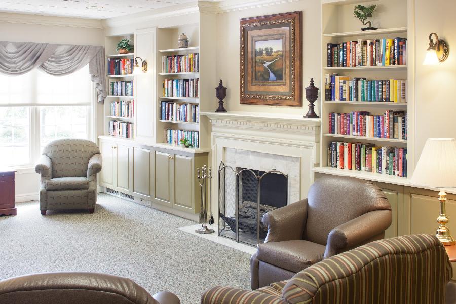 A cozy living room with built-in bookshelves, a fireplace, and comfortable armchairs.