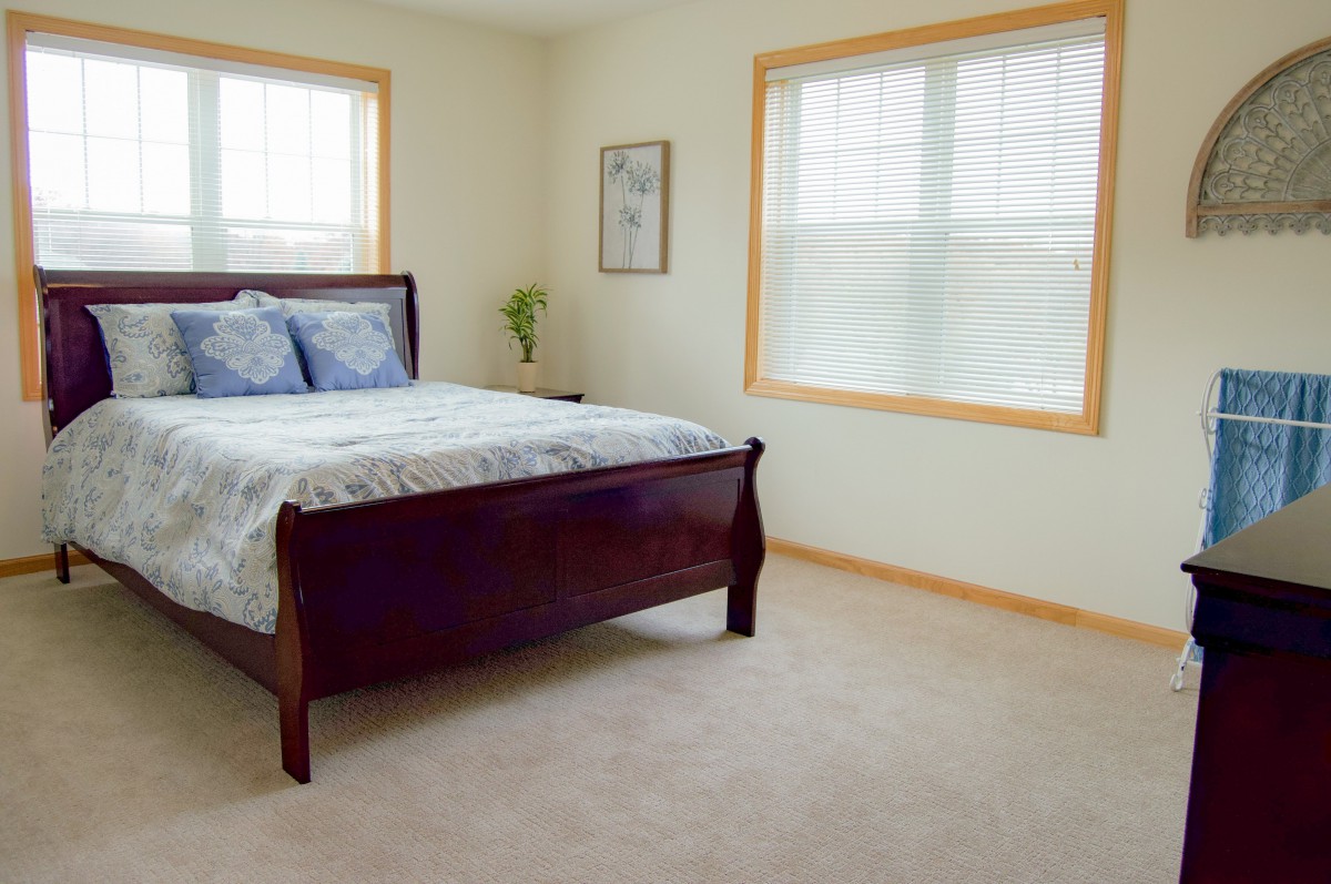 A minimalist bedroom with a wooden bed and large windows.