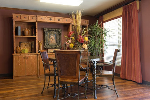 A cozy dining room featuring a wooden table surrounded by chairs, adorned with decorative plants and artwork.