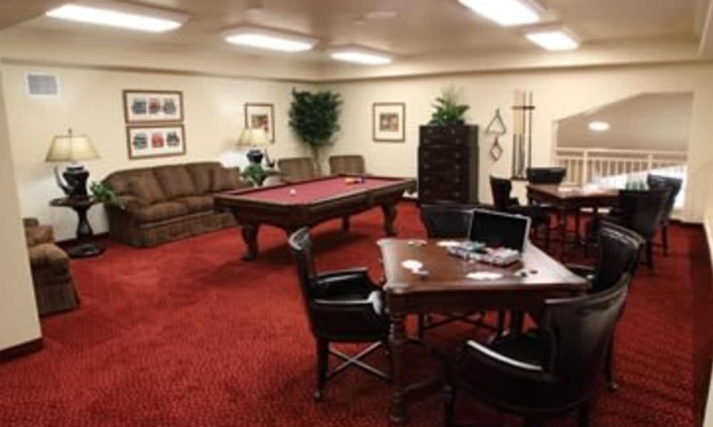 A cozy game room with a pool table, seating area, and indoor plants.