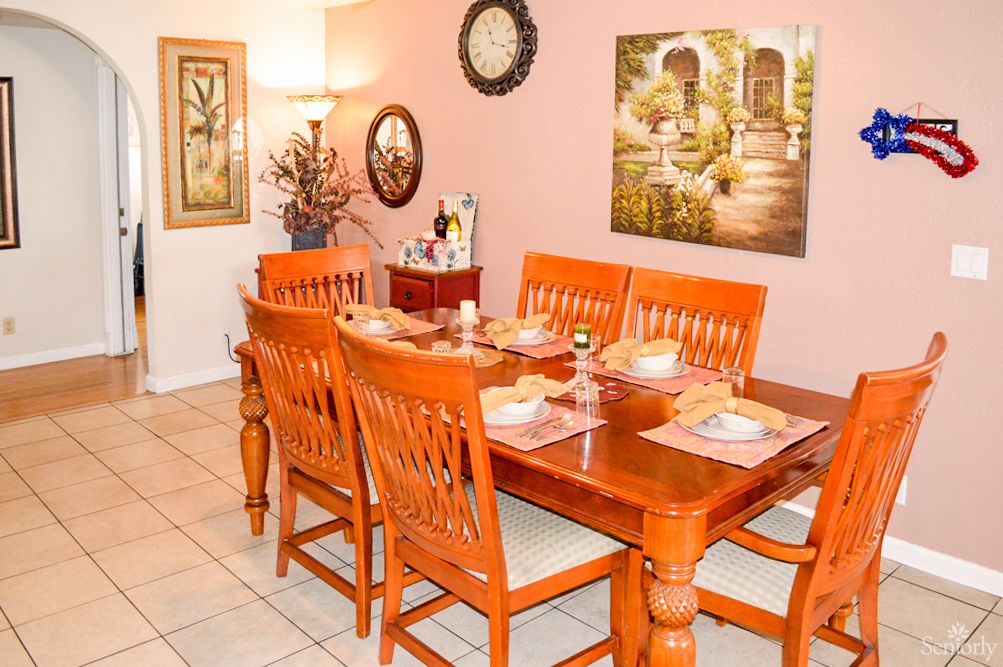 A cozy dining room features a wooden dining set with elegant decor and wall art.