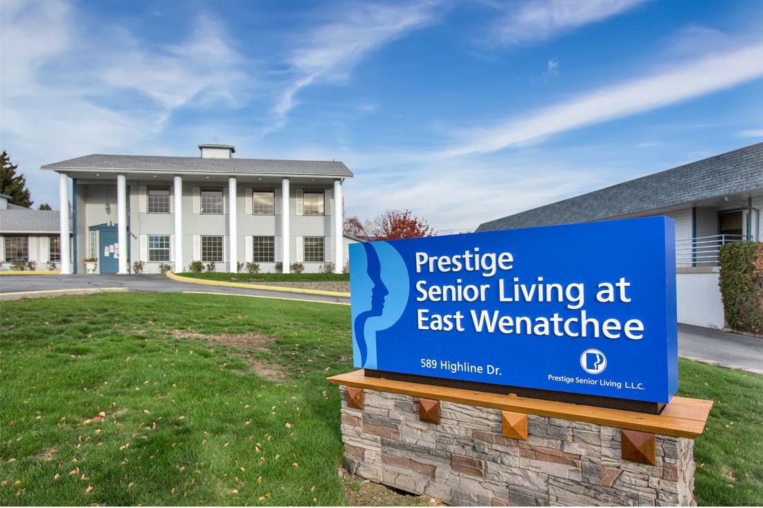 The exterior view of Prestige Senior Living at East Wenatchee featuring a prominent sign and classic architectural style.