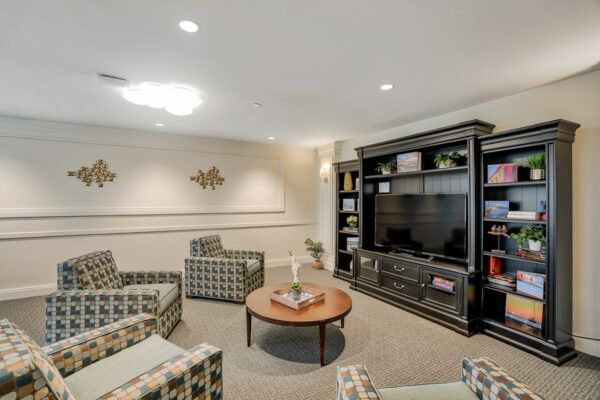A cozy living room with comfortable seating, a large television, and decorative shelves.