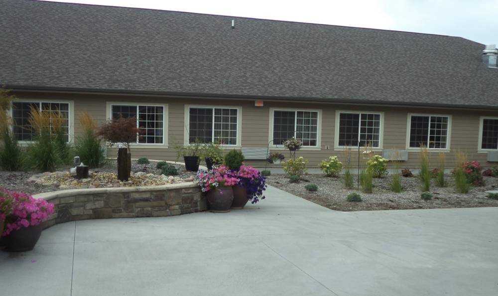 A landscaped area in front of a building with flowers and greenery.