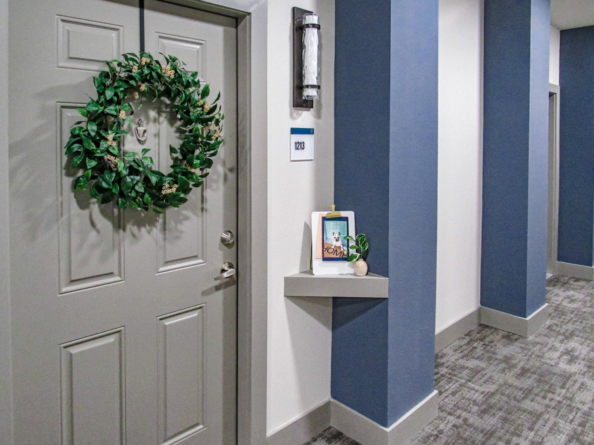 A decorated hallway with a wreath on the door and framed pictures on a shelf.