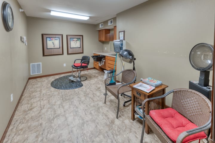 A small office or waiting room with chairs, a desk, and salon equipment.