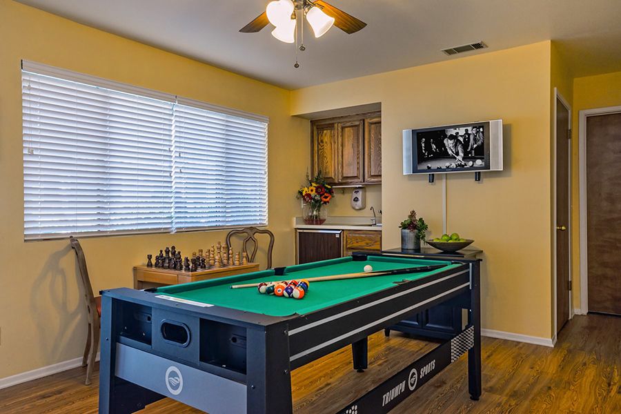 A cozy game room featuring a pool table and chess set, with a television mounted on the wall.