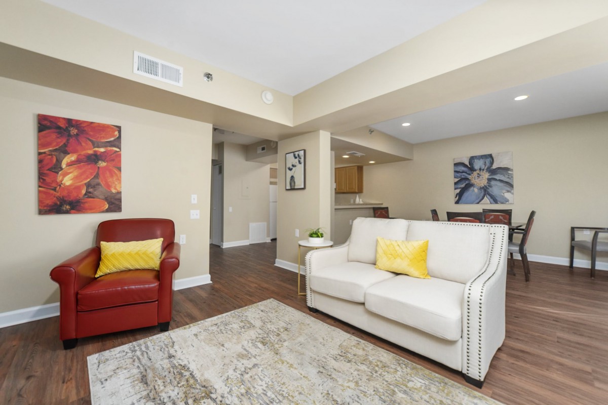 A cozy living room with a white sofa, a red armchair, and colorful artwork on the walls.