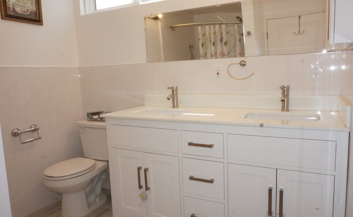 A modern bathroom featuring a white vanity with a large mirror and sleek fixtures.
