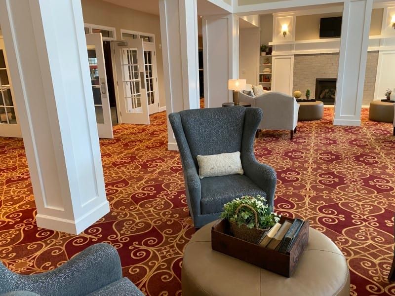 A cozy living room with elegant armchairs and a vibrant carpet, featuring a welcoming fireplace.
