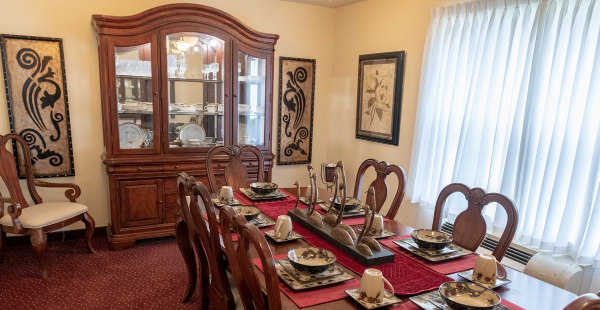 A dining room with a fully set table and a china cabinet in the background.