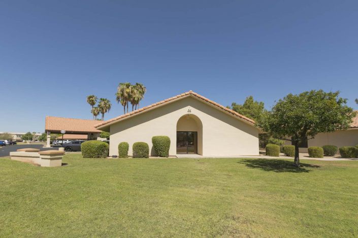 A suburban house with a well-maintained lawn and palm trees.