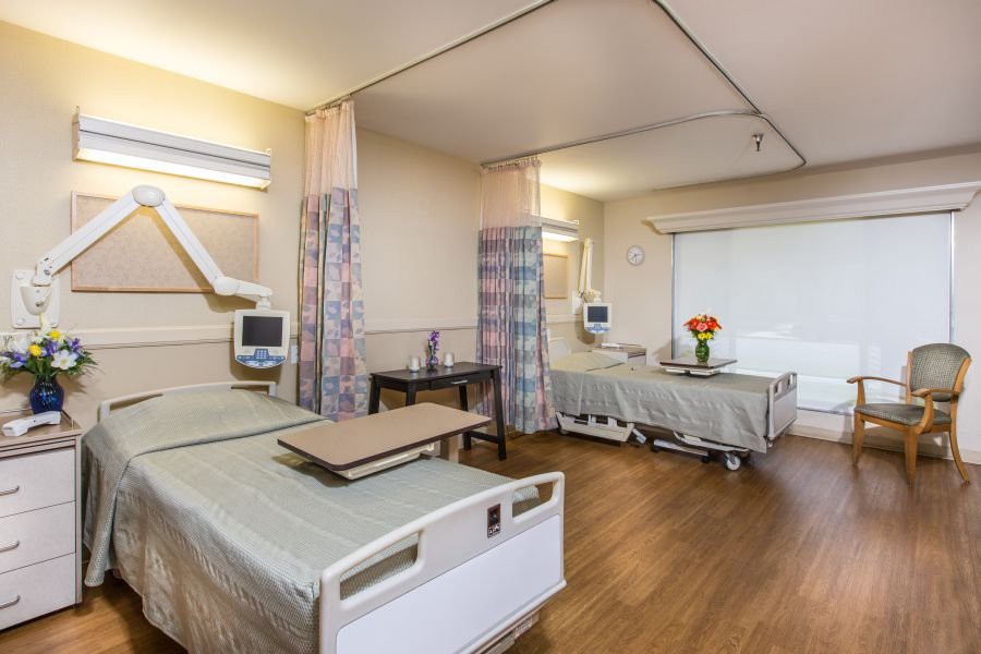 An empty hospital room with patient beds and medical equipment.