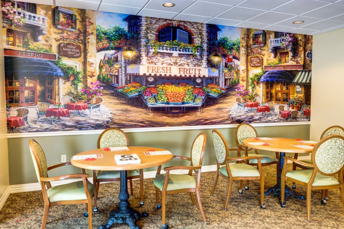 A cozy cafe interior with vibrant mural artwork and neatly arranged seating.