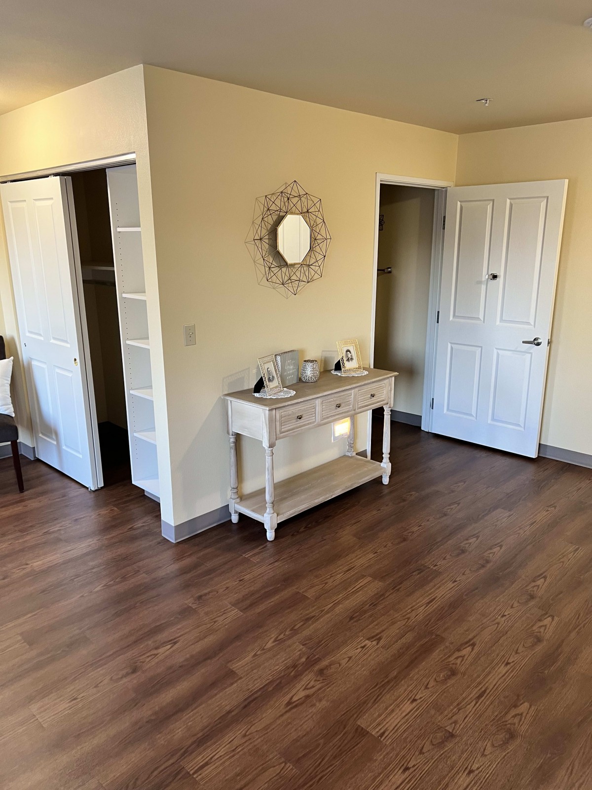A cozy home interior featuring a hardwood floor, a console table with decor items, and a mirror on the wall.