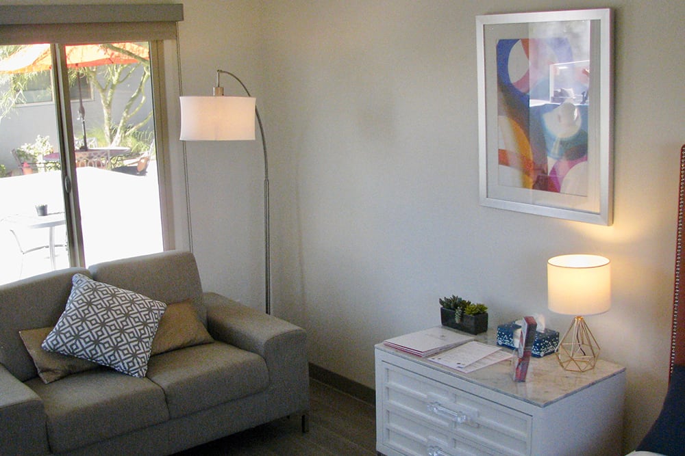 A cozy living room with a sofa, floor lamp, and abstract artwork on the wall.