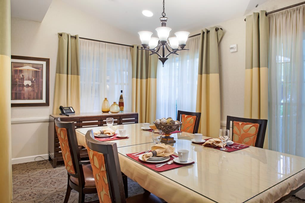 A cozy dining room with a stylish chandelier and neatly arranged table settings.