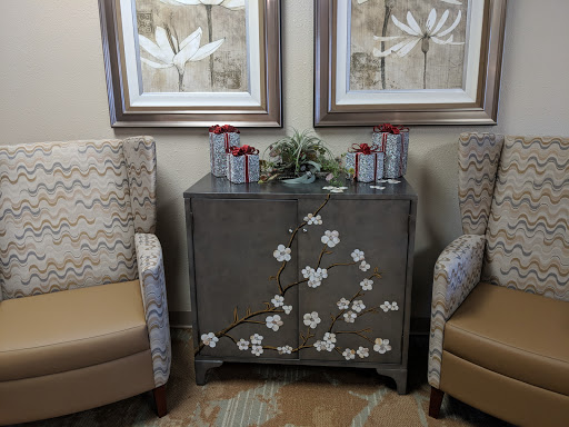A cozy seating area featuring elegant chairs, a decorative cabinet adorned with floral designs, and framed artwork.