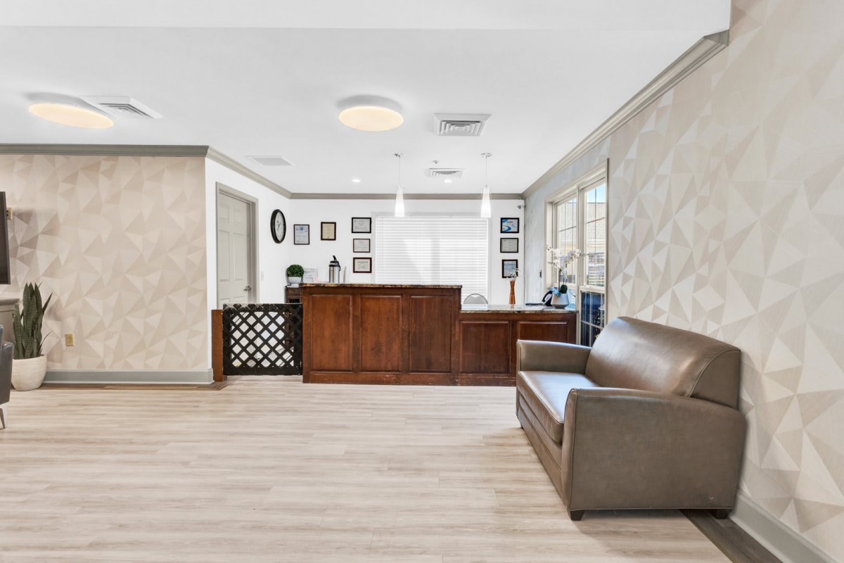 A modern reception area with a wooden desk and a comfortable sofa.