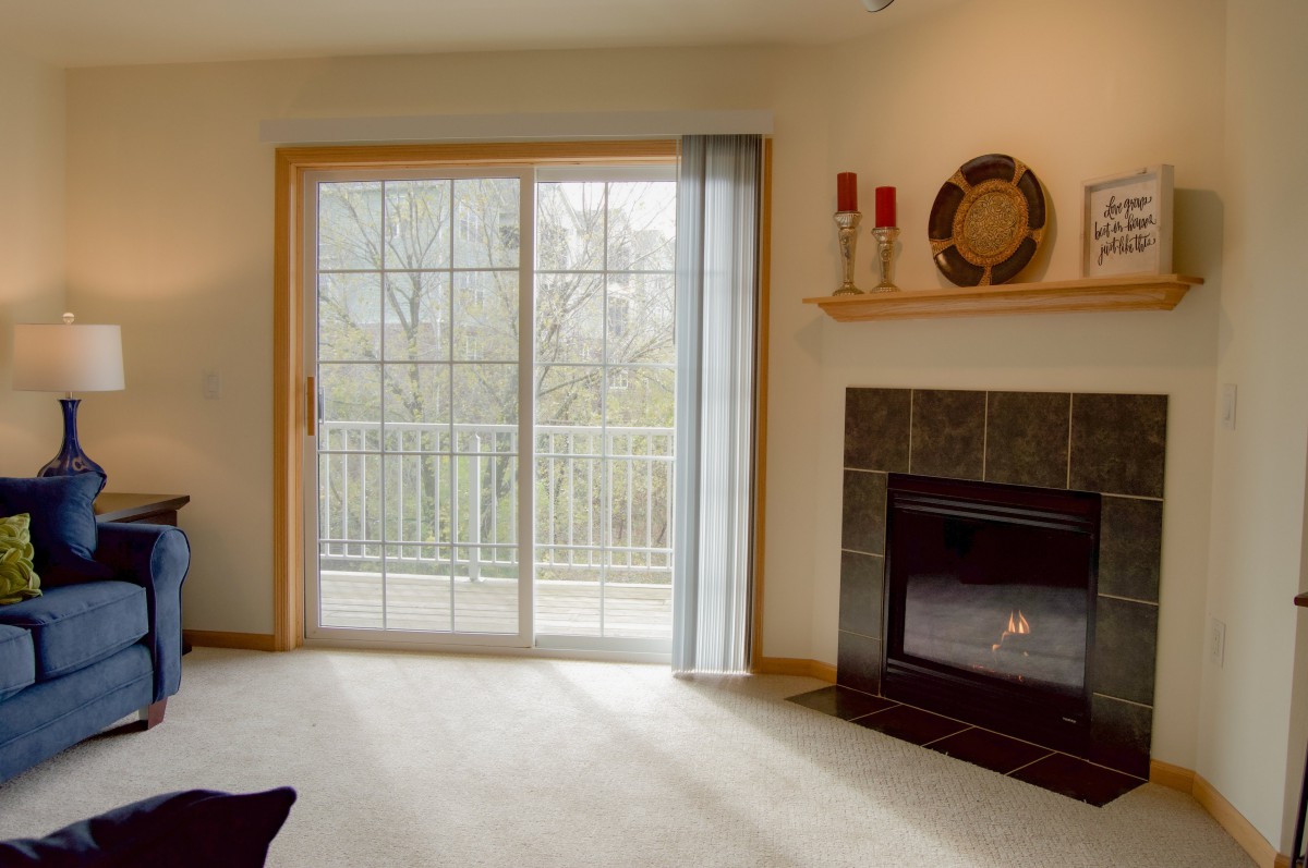 A cozy living room featuring a sliding glass door, a fireplace, and simple decor.
