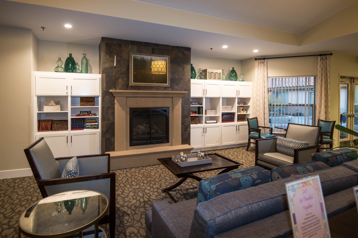 A cozy and modern living room featuring a central fireplace surrounded by shelves, with comfortable seating and stylish decor.