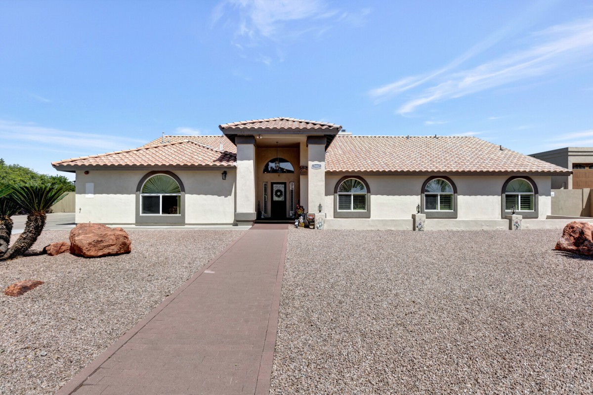 A single-story residential house with a gravel front yard and tiled roof.