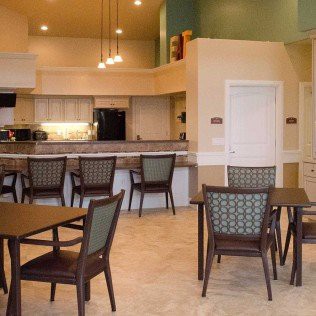 A modern dining area with a kitchen and neatly arranged tables and chairs.