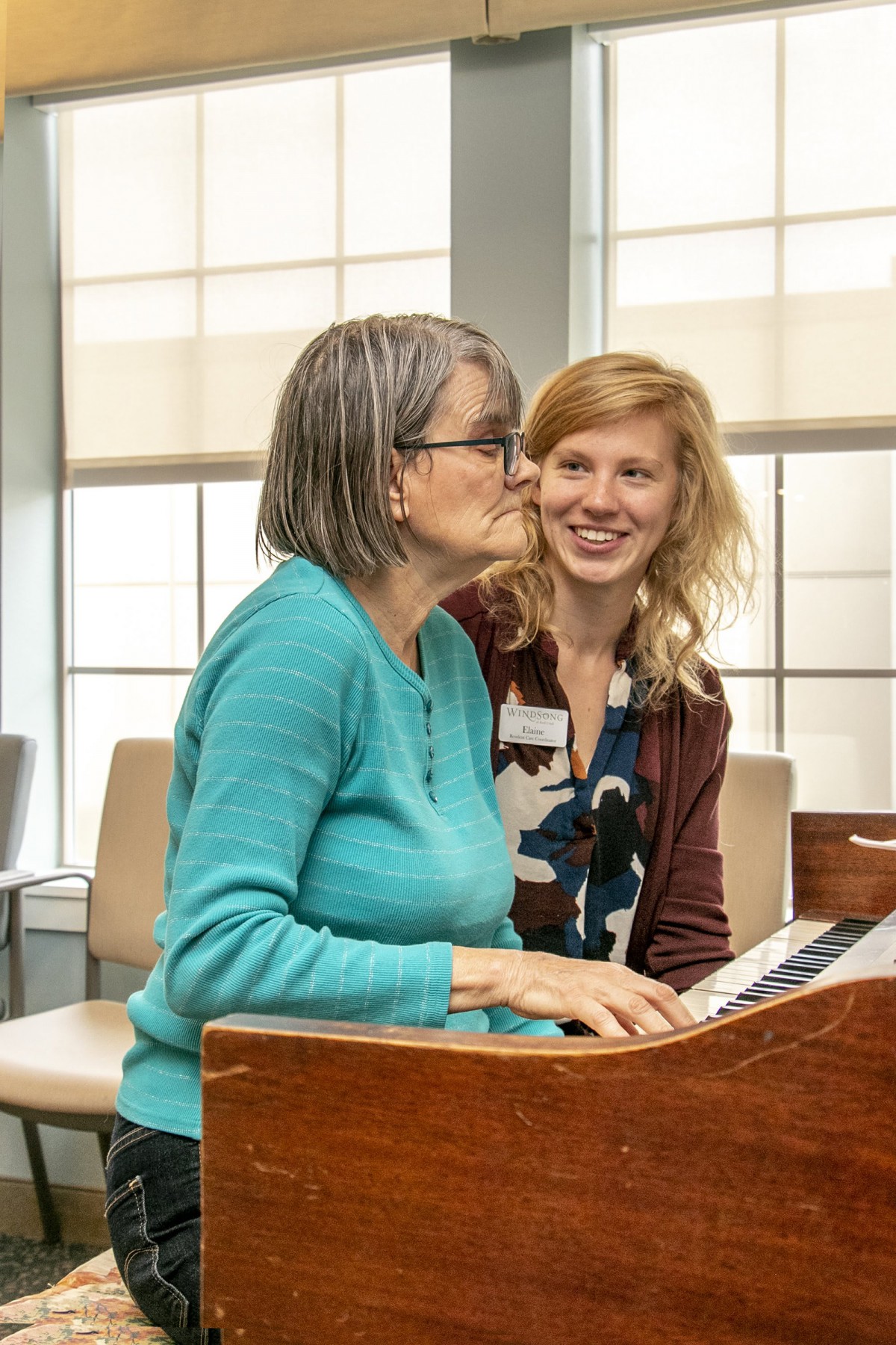 Two women enjoying playing the piano together indoors.