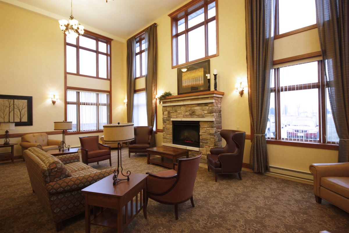 A cozy living room with a stone fireplace and large windows, featuring elegant furniture and high ceilings.