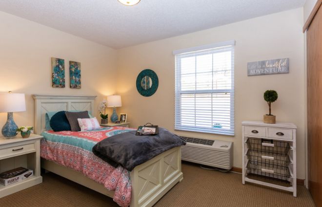 A cozy, well-decorated bedroom with a colorful bedspread and ambient lighting.
