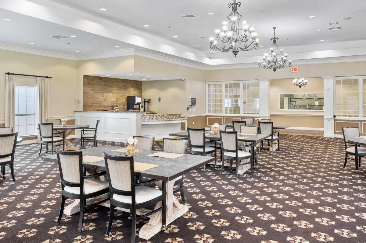 Elegantly designed restaurant dining area with chandeliers and carpeted flooring.